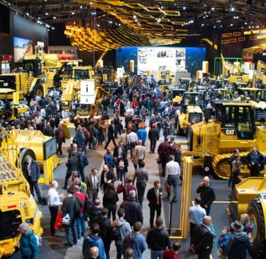 a large group of people standing around a large group of yellow construction equipment