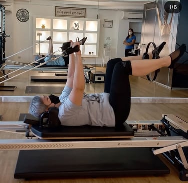 Client performing reformer arm and leg coordination exercise under the guidance of instructor Maalz