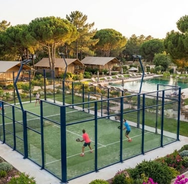 a couple of people playing padel on a padel court in a camping