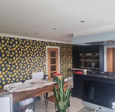 Kitchen in a residential home, with a large wall covered in dark-blue and lemon motif wallpaper.