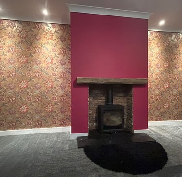 A painted burgundy fireplace, with surrounding brown, botanical wallpaper.