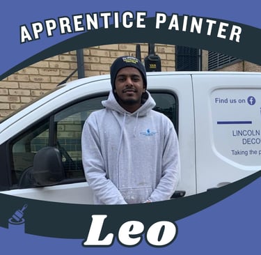 Portrait of Leo, an apprentice painter, standing and smiling in front of a van.