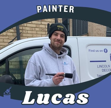 Portrait of Lucas, an LPAD painter, holding a paintbrush whilst smiling, in front of a van..