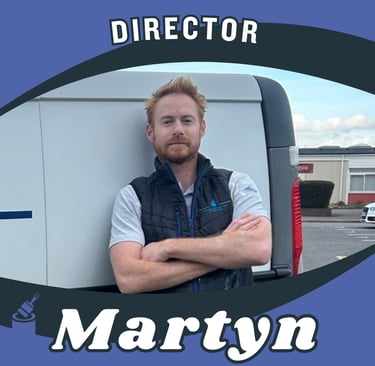 Portrait of Martyn, company director, smiling and leaning against a van.