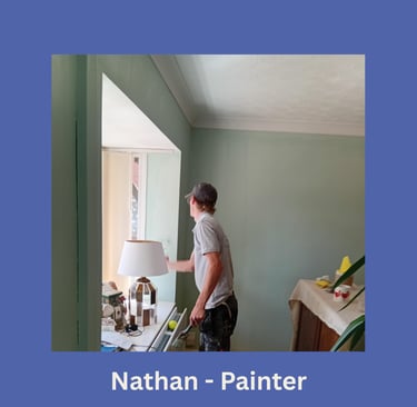 Portrait of Nathan, an LPAD painter, standing and painting a window frame and facing away.