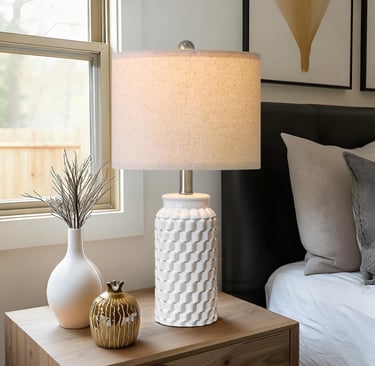 Modern white ceramic bedside table lamp with textured honeycomb base on a wooden nightstand.