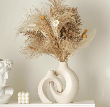 Minimalist beige interlocking ceramic donut vases with dried pampas grass and flowers.