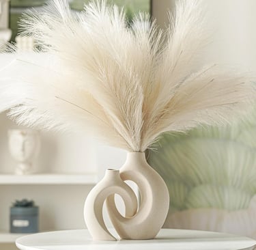 Minimalist beige ceramic donut vase with fluffy artificial pampas grass decor on a white table.