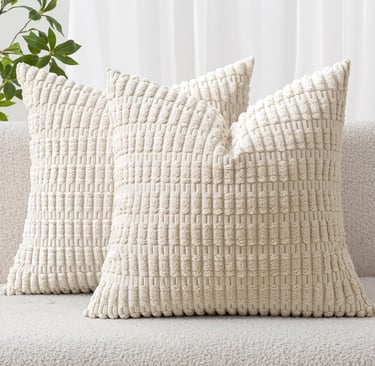 Two cream-colored textured corduroy decorative throw pillows on a soft white boucle sofa.