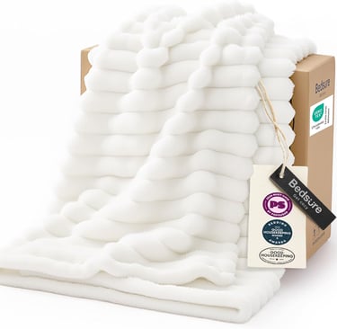 White faux fur throw blanket draped over a cardboard box, featuring a soft ribbed texture and brand tags.
