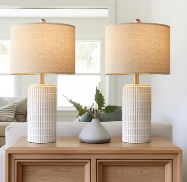 Pair of modern ceramic table lamps with textured white bases and linen shades on a wooden dresser.
