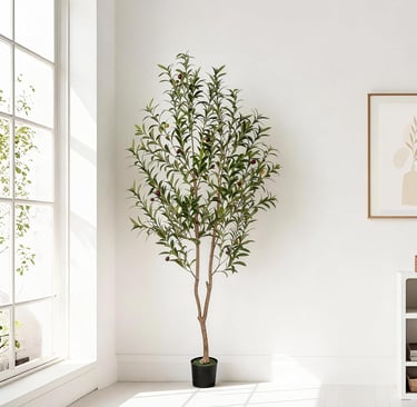 A tall artificial olive tree with realistic green leaves in a black pot stands in a bright, modern room.