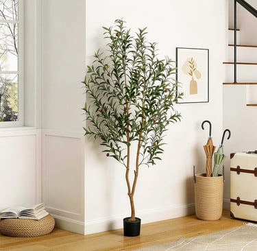 Tall artificial olive tree in a black pot decorating a modern home entryway with white walls.