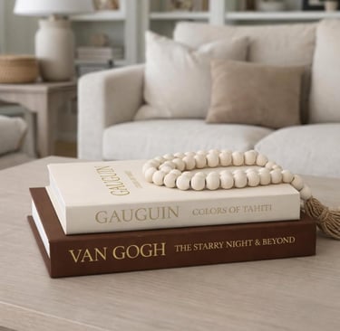 Van Gogh and Gauguin coffee table books styled with wood beads in a neutral living room.