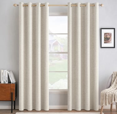 Beige textured linen blackout curtains with metal grommets hanging on a wooden rod over a window.