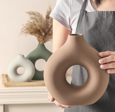 A person holding a brown ceramic donut vase featuring a minimalist nordic style for home decor.