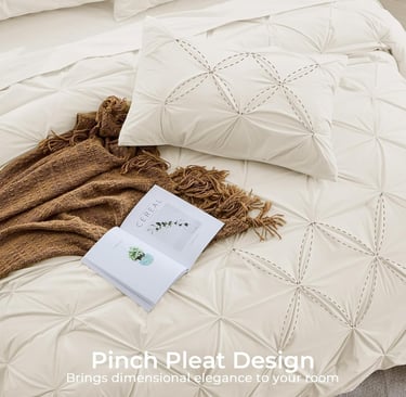 White pinch pleat comforter set with decorative stitching and a brown throw blanket.