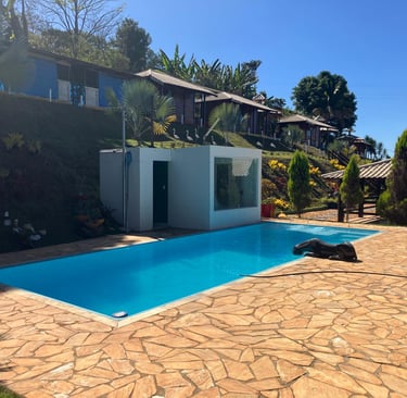 Luxury outdoor swimming pool at a hillside resort with blue water and stone patio.