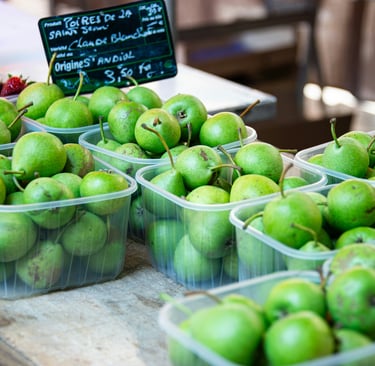Fresh green pears displayed in clear plastic punnets at a farmers market fresh produce packaging