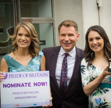 ITV presenters holding a Pride of Britain nomination sign and award trophy outside a studio.