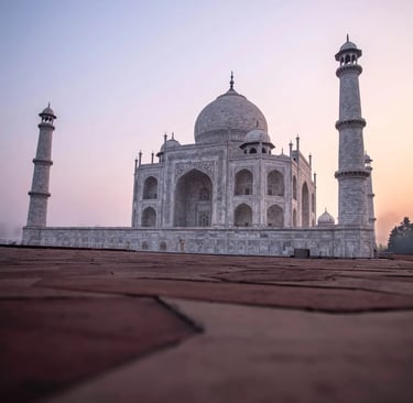 Low angle view of the Taj Mahal in Agra at sunrise with white marble domes and minarets.