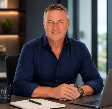 Professional recruitment consultant sitting at a desk with a laptop, notebook, and DeHaan Recruitment mug.