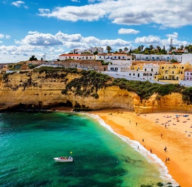 Scenic view of Carvoeiro beach in Portugal with golden sand, turquoise water, and white houses.