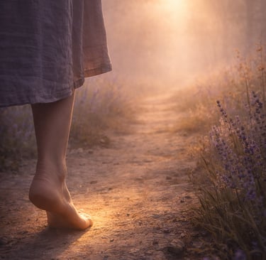 Barefoot person walking on a misty dirt path through lavender fields at golden hour sunrise.
