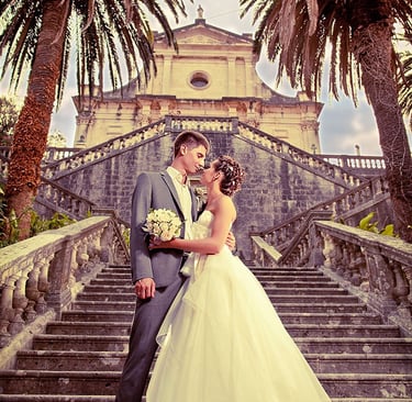 Bride and groom on grand stone staircase at historic church in Kotor, Montenegro, wedding ceremony p