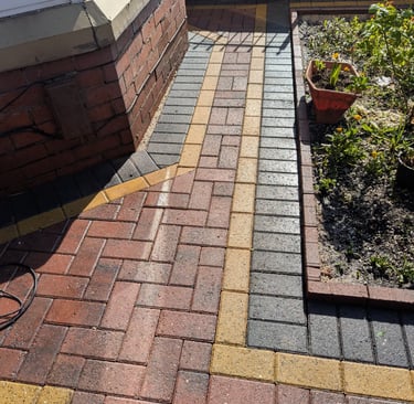 After Red and charcoal block paving front with yellow decorative borders next to a garden bed.