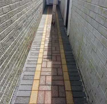 After alleyway featuring multi-colored block paving stones between two light-colored brick walls.