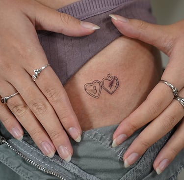 Tatuaje fineline en Madrid de dos corazones estilo medallón con iniciales en trazo 