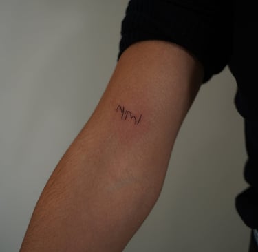 Tatuaje fineline en Madrid con lettering mimi en trazo manuscrito ultrafino en el antebrazo