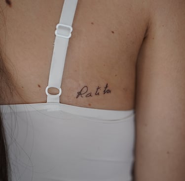 Tatuaje fineline en Madrid con lettering Ratita en cursiva fina en la espalda