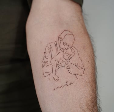 Tatuaje fineline en Madrid de figura masculina abrazando a un bebe con lettering 