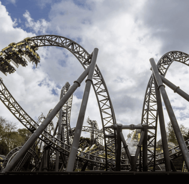 A Roller coaster in the shape of eyes and a smile with a cart on a loop to the left  