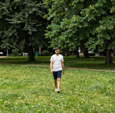 Campus scene with students walking under bright blue sky and leafy trees.