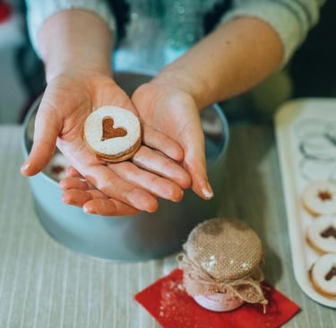 Manos sosteniendo una galleta Linzer en forma de corazón con azúcar glas,