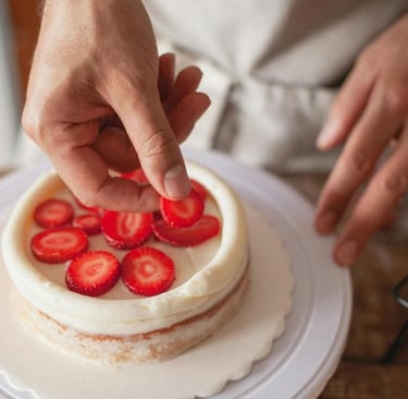 Pastelero decorando un pastel con crema y fresas