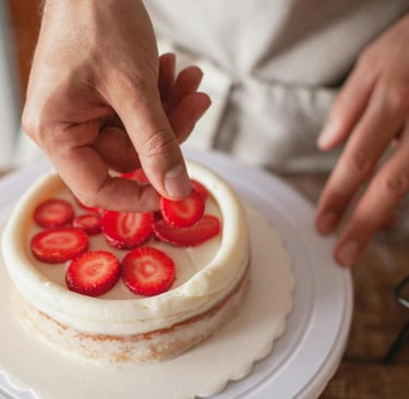 epostero decorando una naked cake con frosting blanco y rodajas frescas