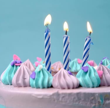 Torta de cumpleaños en tonos morado y azul, con velas encendidas y decoración de frosting en remolin