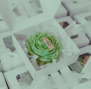 Vela artesanal de rosa verde en una caja blanca con una etiqueta personalizada para recuerdos
