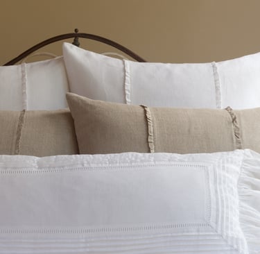 Linen bedding in soft morning light in a French Mediterranean bedroom.