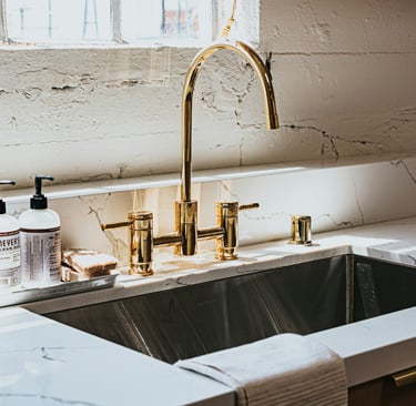 Kitchen sink with an unlacquered brass tap developing a natural patina.
