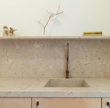 Kitchen where the stone worktop continues up the wall as a restrained splashback.