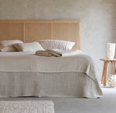 linen bedding, wood headboard, and plaster wall.