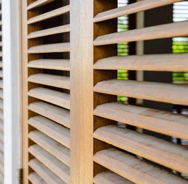 Filtered morning light through shutters in a Mediterranean bedroom.