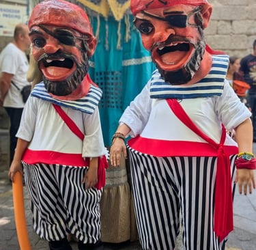 two cabezudos in grotesque pirate costumes with large heads