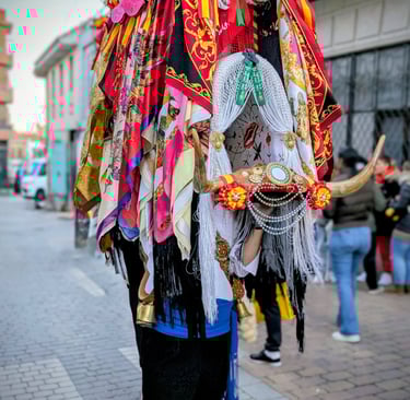A person wearing the wooden frame of La Vaquilla headdress featuring bull-horns, floral fabrics, and colorful ribbons.