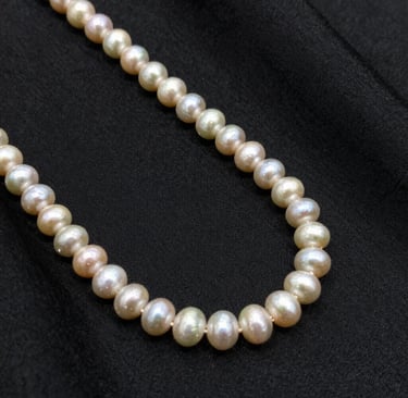 Close-up of a delicate gold ring with a small gemstone resting on creamy beige fabric, reflecting soft light